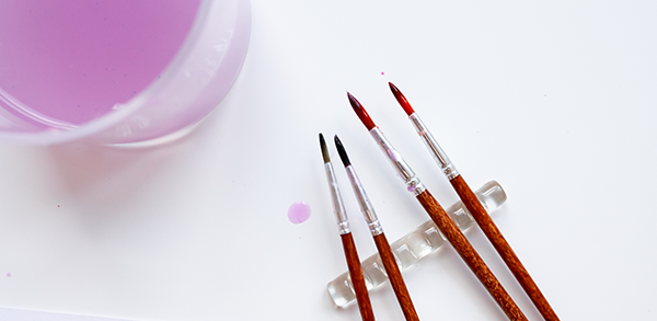 vecteezy_assorted-artist-brushes-with-glass-of-purple-water-on-white_71602358